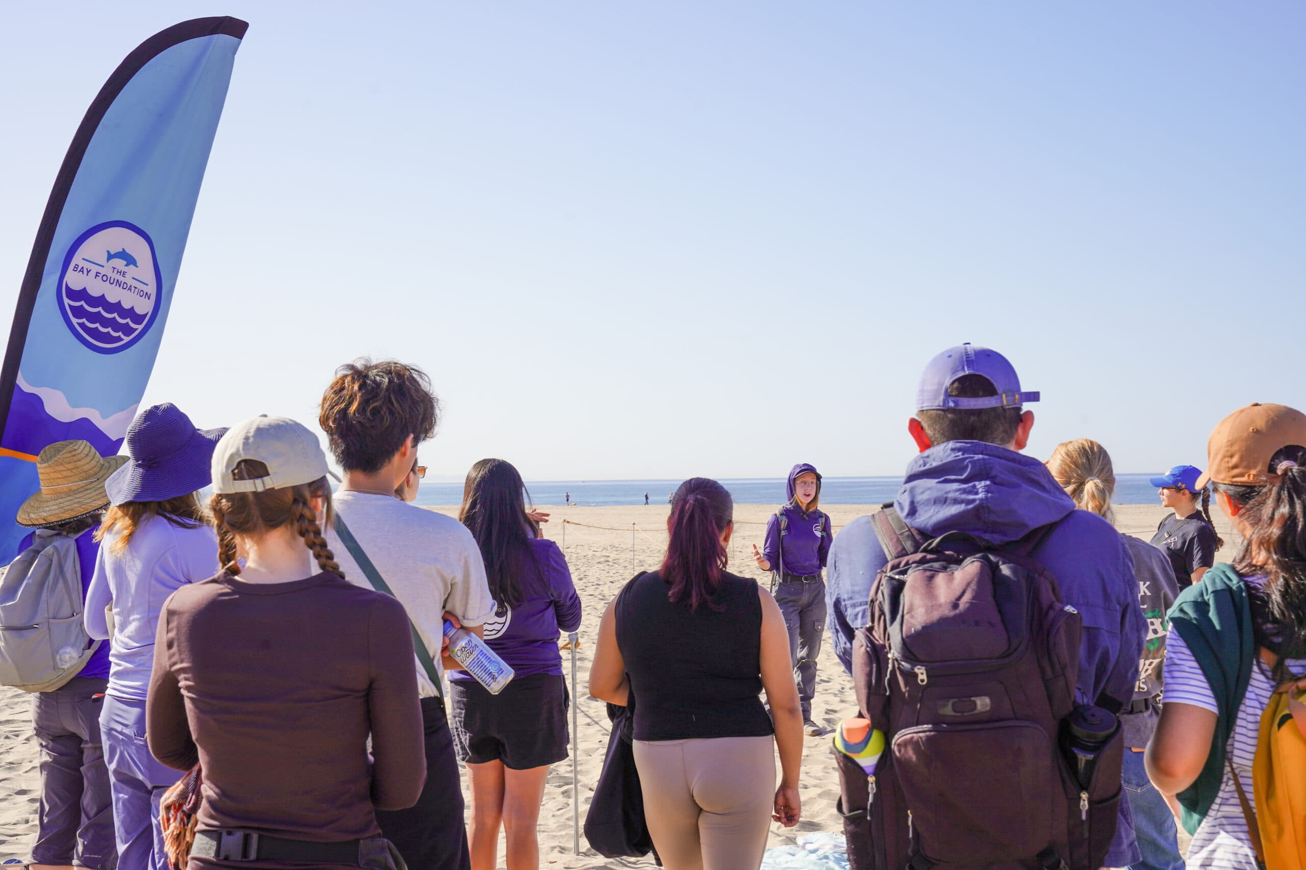 group surrounding TBF staff at the dunes, TBF flag in the front